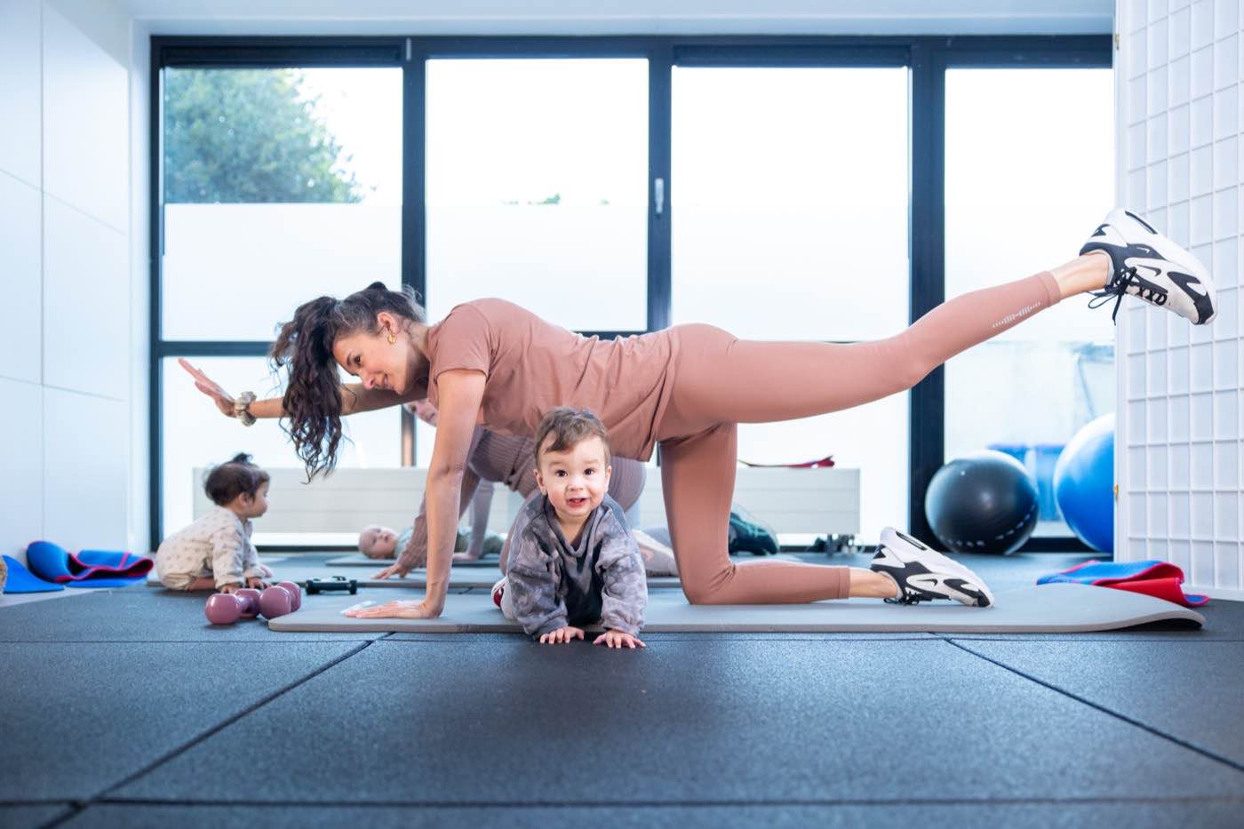 Een moeder traint op een mat terwijl haar baby voor haar zit